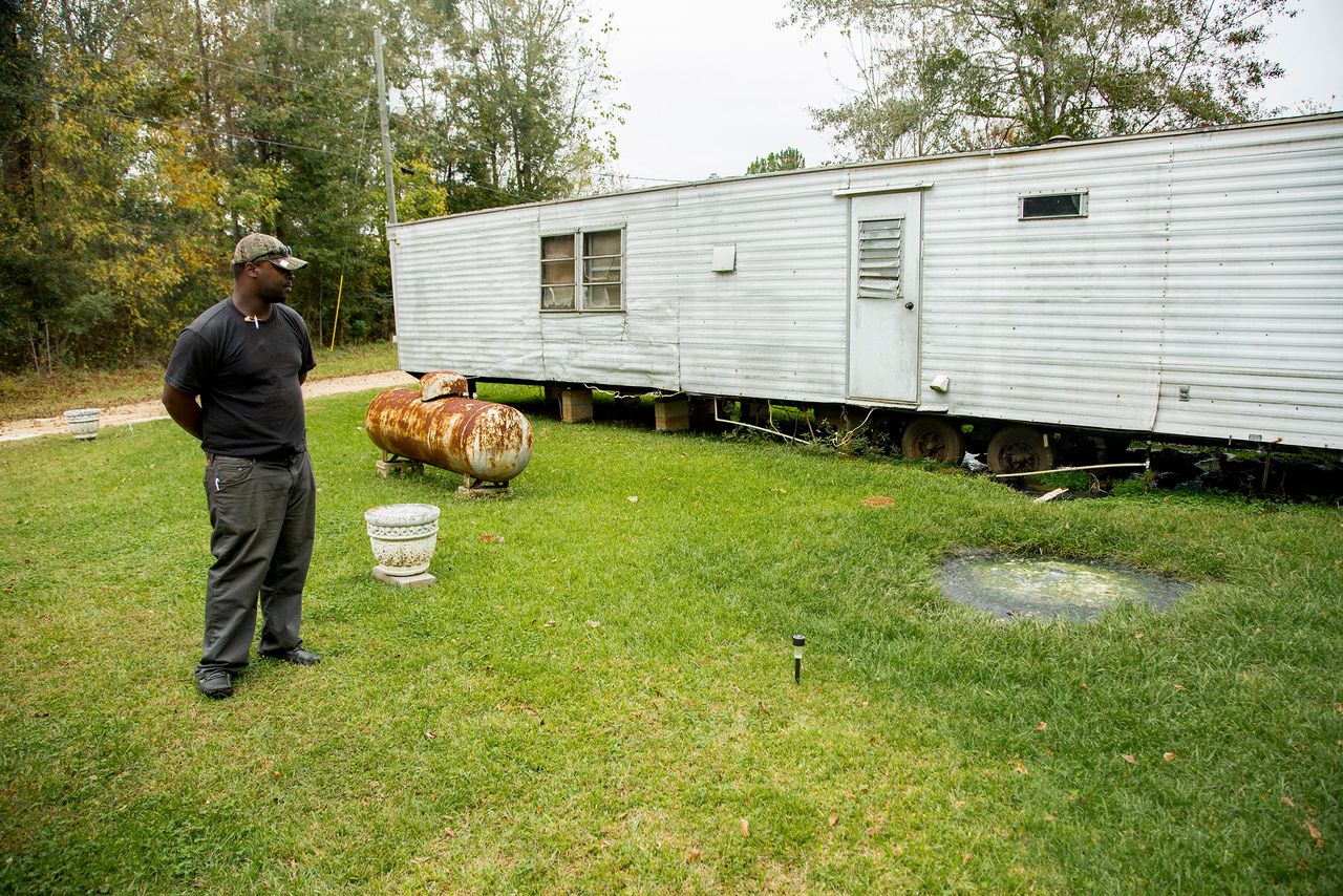 Community activist Aaron Thigpen examines raw waste pooling next to a mobile home.