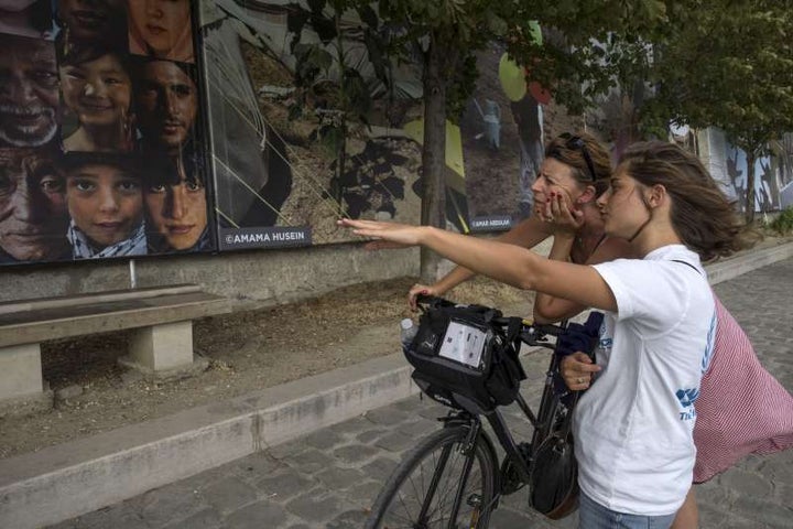 A UNHCR volunteer indicates to a visitor some of the main themes of Reza’s exhibition along the Seine’s shore in Paris. 