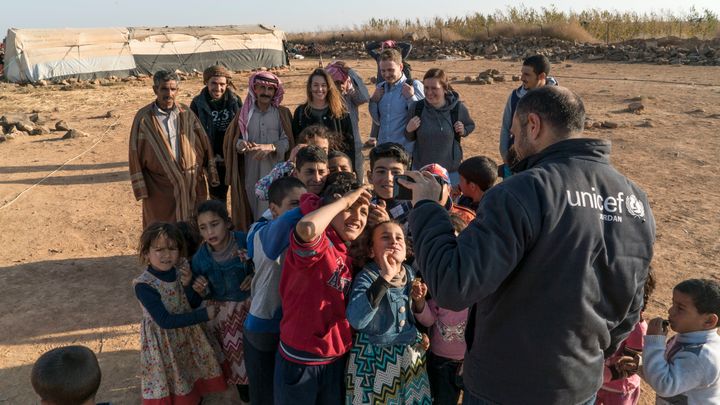 Children at a refugee camp near the Jordanian border with Syria play with a Unicef worker