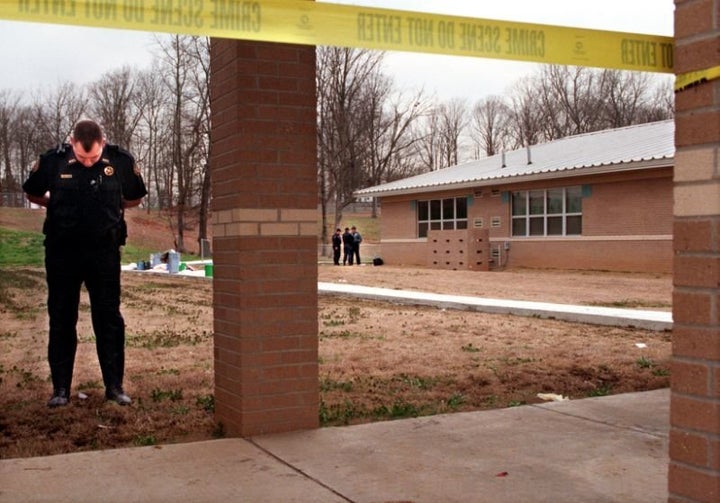 A police officer stands at the perimeter of the crime scene.