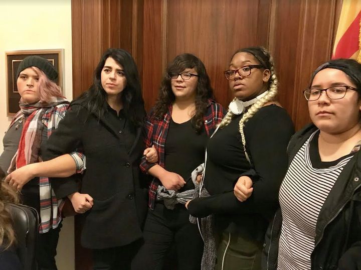 <p>Young people blocking the door of Senator Jeff Flake, awaiting his arrival to share their frustration regarding the coming tax bill</p>