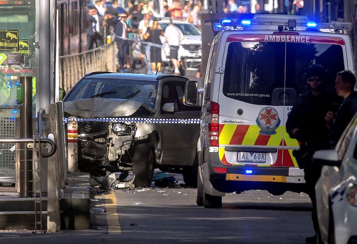Australian police stand near a crashed vehicle after they arrested the driver of a vehicle that ploughed into pedestrians.