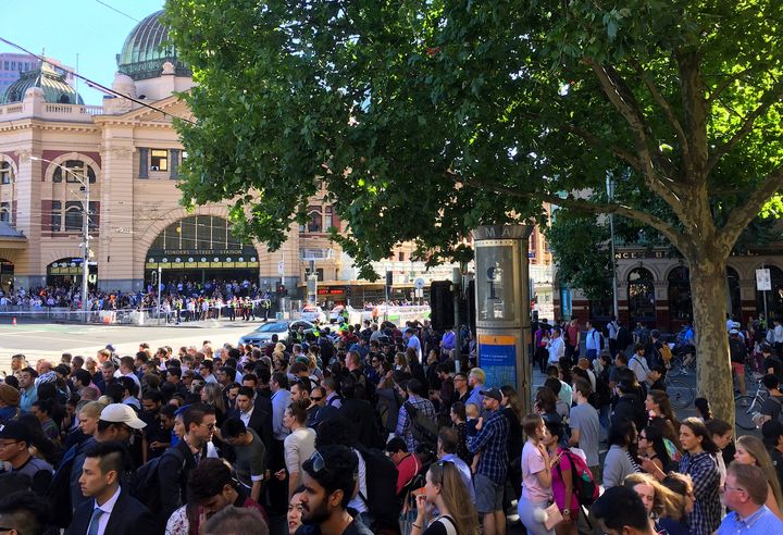 Members of the public stand behind police tape after Australian police said on Thursday they have arrested the driver of a vehicle that ploughed into pedestrians in Melbourne.