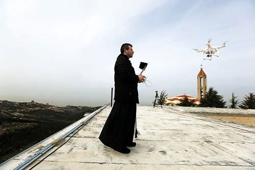 <p><em>A Maronite priest flies a drone to film and photograph processions and prayers at the Saint Maroun Monastery of Annaya, north of Beirut (courtesy AFP)</em></p>