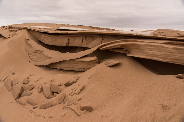 The wafer thin layers of sand, bending under the stress of gravity.