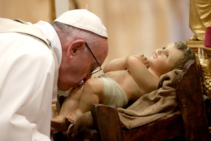 Pope Francis kisses the Baby Jesus as he arrives at the St. Peter's Basilica for the Christmas Eve Mass.