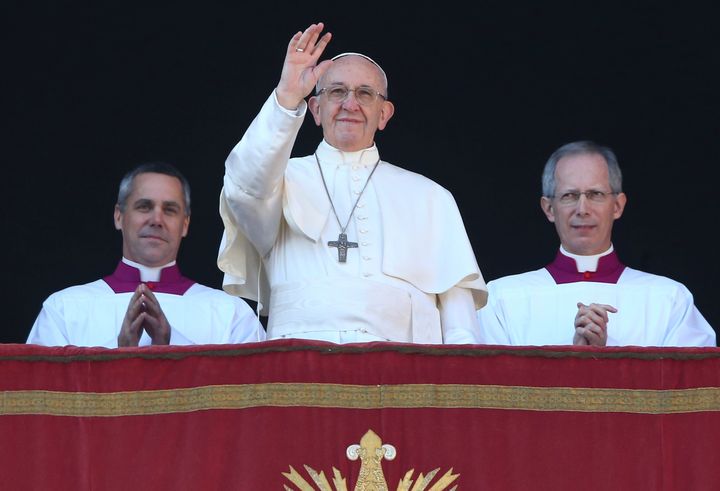 Pope Francis waves as he leads the "Urbi et Orbi" (to the city and the world) message from the balcony overlooking St. Peter's Square at the Vatican on December 25, 2017.