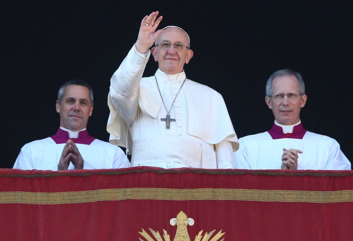 Pope Francis waves as he leads the "Urbi et Orbi" (to the city and the world) message from the balcony overlooking St. Peter's Square at the Vatican on December 25, 2017.