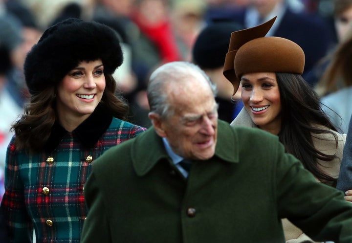 Meghan Markle walks alongside the Duchess of Cambridge as Prince Philip gestures to the crowd.