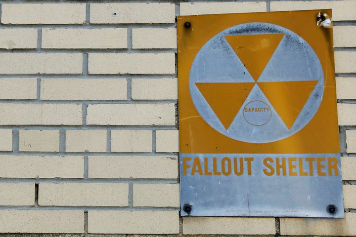 A yellow nuclear fallout shelter sign hangs on a building in Brooklyn.