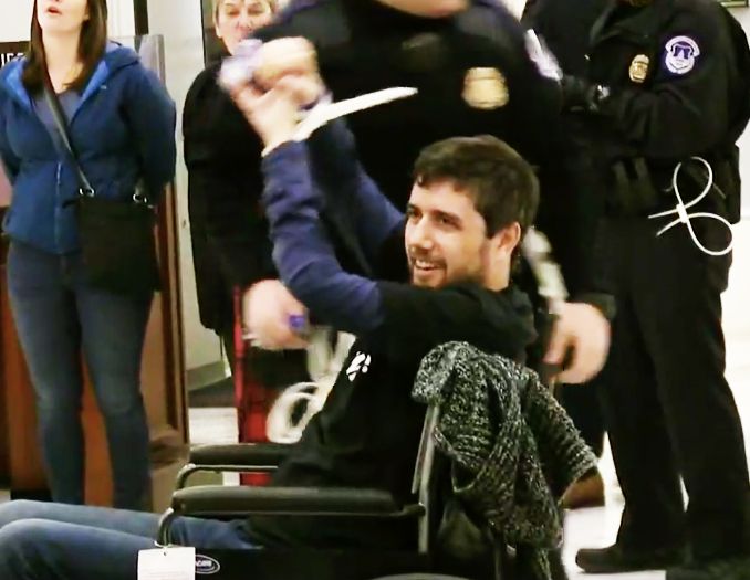 Ady Barkan raises his fists in triumph after getting arrested while protesting the tax bill on Dec. 18, 2017, his 34th birthday.