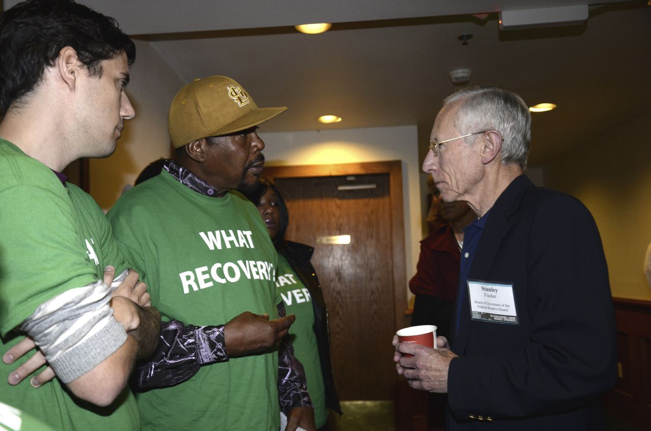 Reggie Rounds of Ferguson, Missouri (center), speaks to Federal Reserve Vice Chair Stanley Fischer (right), as Ady Barkan (left) looks on at Fed Up's inaugural event in August 2014 in Wyoming.