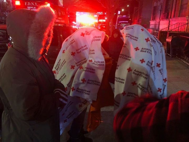 Displaced residents stand outside in freezing temperatures while firefighters fight one of the worst blazes New York City has seen in years.