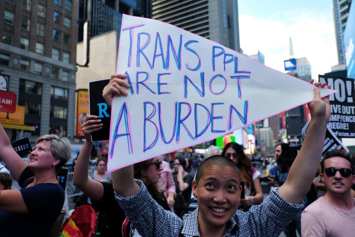 Protesters display placards against President Donald Trump during a demonstration in front of the U.S. Army career center in New York City's Times Square on July 26, 2017.