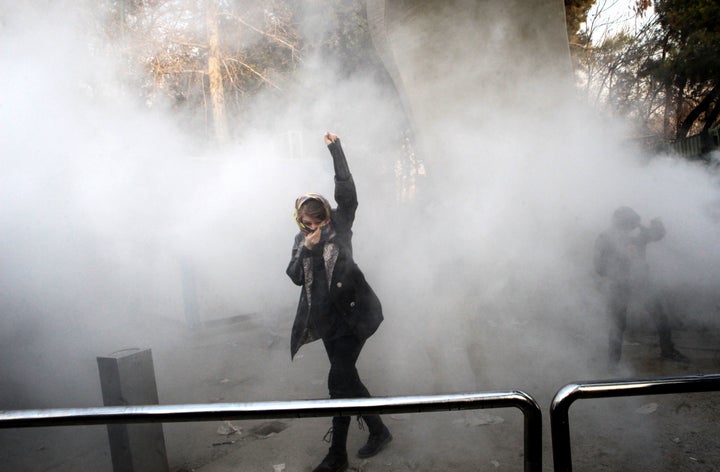 An Iranian woman raises her fist amid the smoke of tear gas at the University of Tehran during a protest driven by anger over economic problems on December 30, 2017.