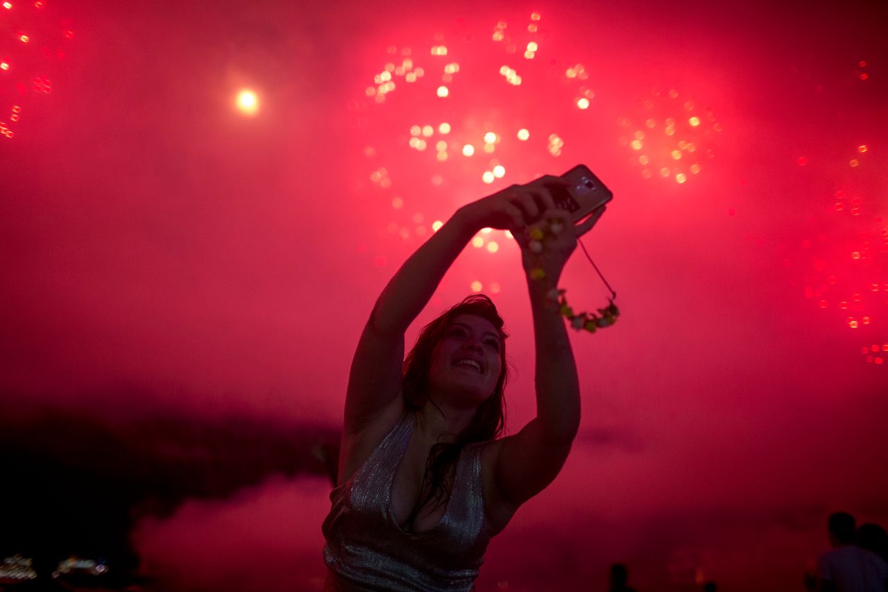 A woman takes a selfie during New Year's celebrations at Copacabana beach in Rio de Janeiro on January 1, 2018.