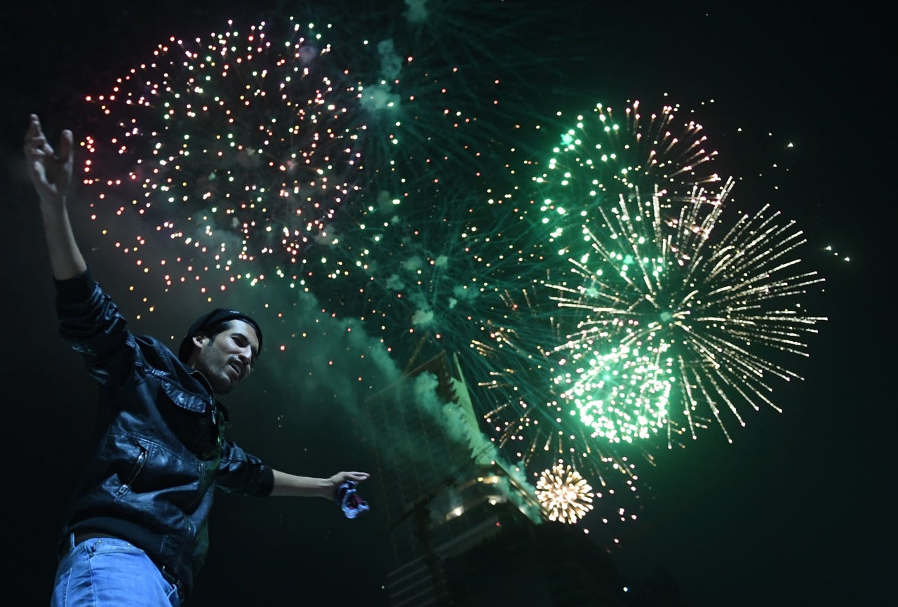 A Pakistani man dances on a street next to fireworks as he celebrates the new year in the port city of Karachi early on January 1, 2018.