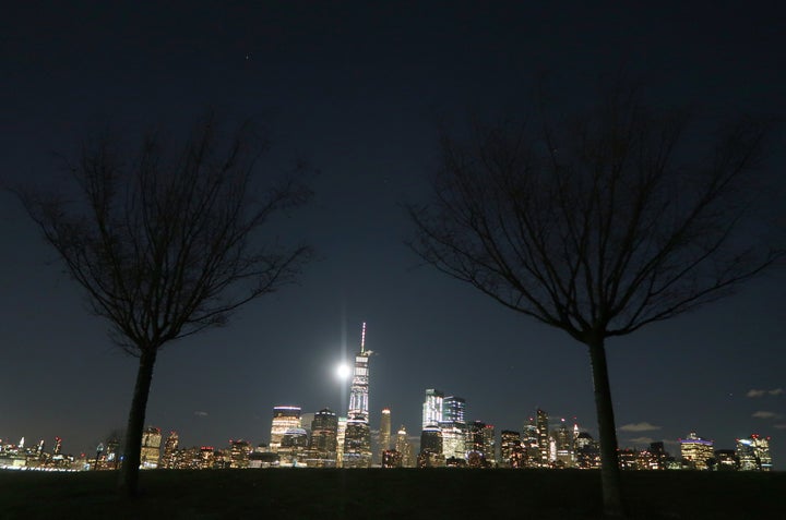 The supermoon rises behind the skyline of lower Manhattan and One World Trade Center in New York City.