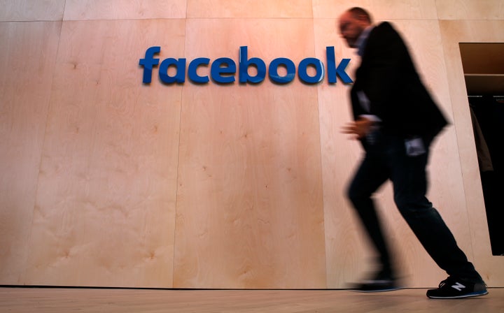 A man walks in front of the Facebook logo at the Facebook Innovation Hub in Berlin.