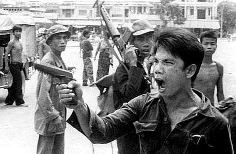 A Khmer Rouge soldier waves his pistol and orders store owners to abandon their shops in Phnom Penh, Cambodia on April 17, 19