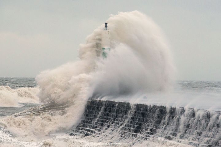 Waves crash over the stone jetty wall in Aberystwyth in west Wales as Storm Eleanor hits