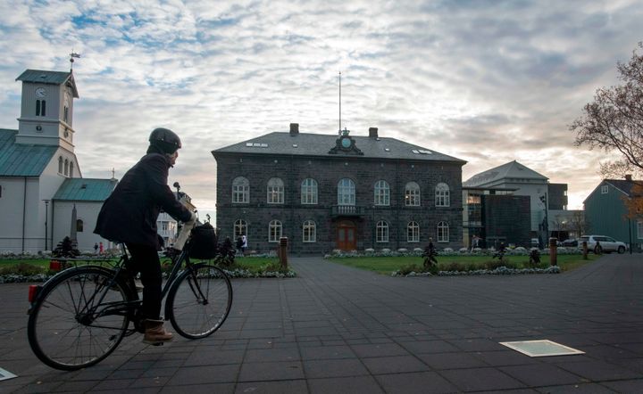 A woman cycles past the Althingi Parliament building in Reykjavik, Iceland 