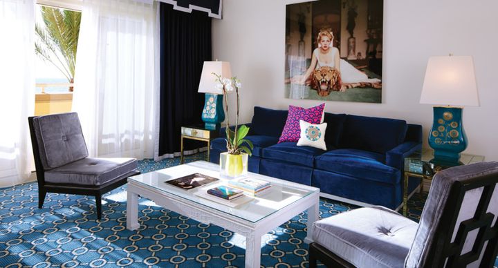 Above, a deep blue velvet sofa adds bold color that doesn’t take over the room in a space at Eau Palm Beach designed by Jonathan Adler.