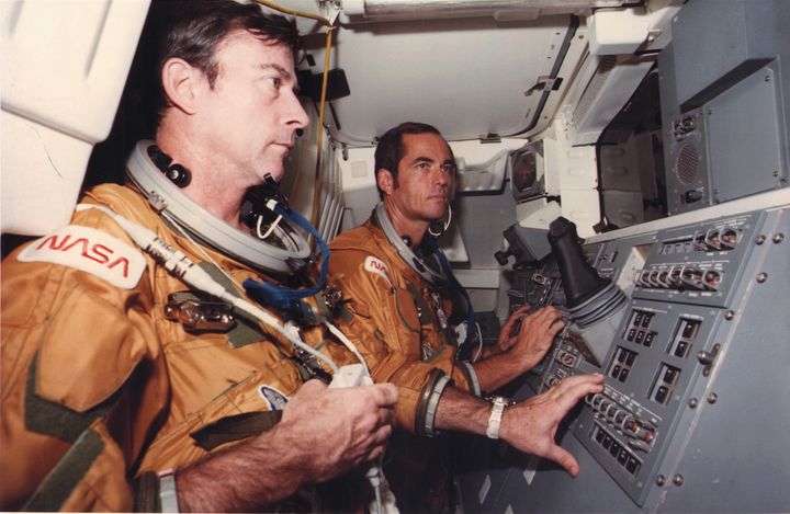 John Young, left, and Robert Crippen, right, look toward the cargo bay of NASA's Space Shuttle Orbiter 102 in October 1980.