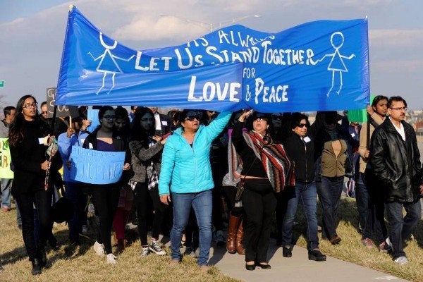 Participants in a vigil for Kuchibhotla hold a sign reading "Let Us Stand Together For Love & Peace" in the Kansas City s