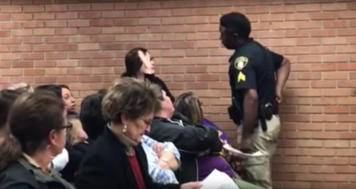 A woman identified as middle school teacher Deyshia Hargrave is confronted by a law enforcement officer during a school board