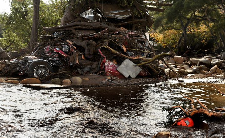A mangled car along with other debris stacked up against a tree in Montecito 