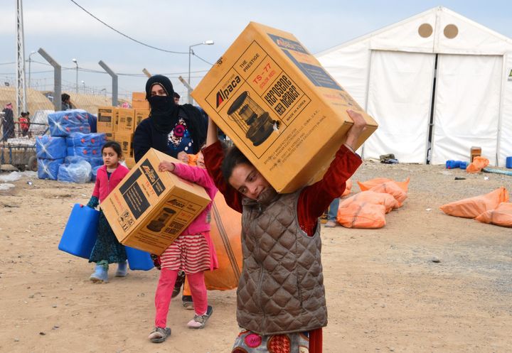 A boy carries a kerosene heater during winterization distributions in January 2018 at an internal displacement camp in Tikrit, Iraq, where families await safe return following the conflict with ISIS. 