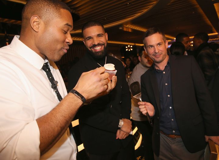 Drake (center) smiling at a cupcake.