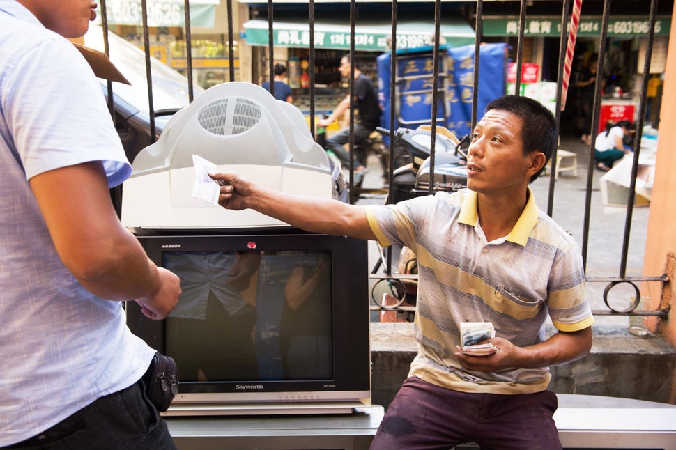 Mr. Wang, an informal recycler, pays another recycler for delivering a washing machine in Shanghai. Recyclers like Mr. Wang have been credited with keeping a significant amount of trash out of Shanghai's landfills.