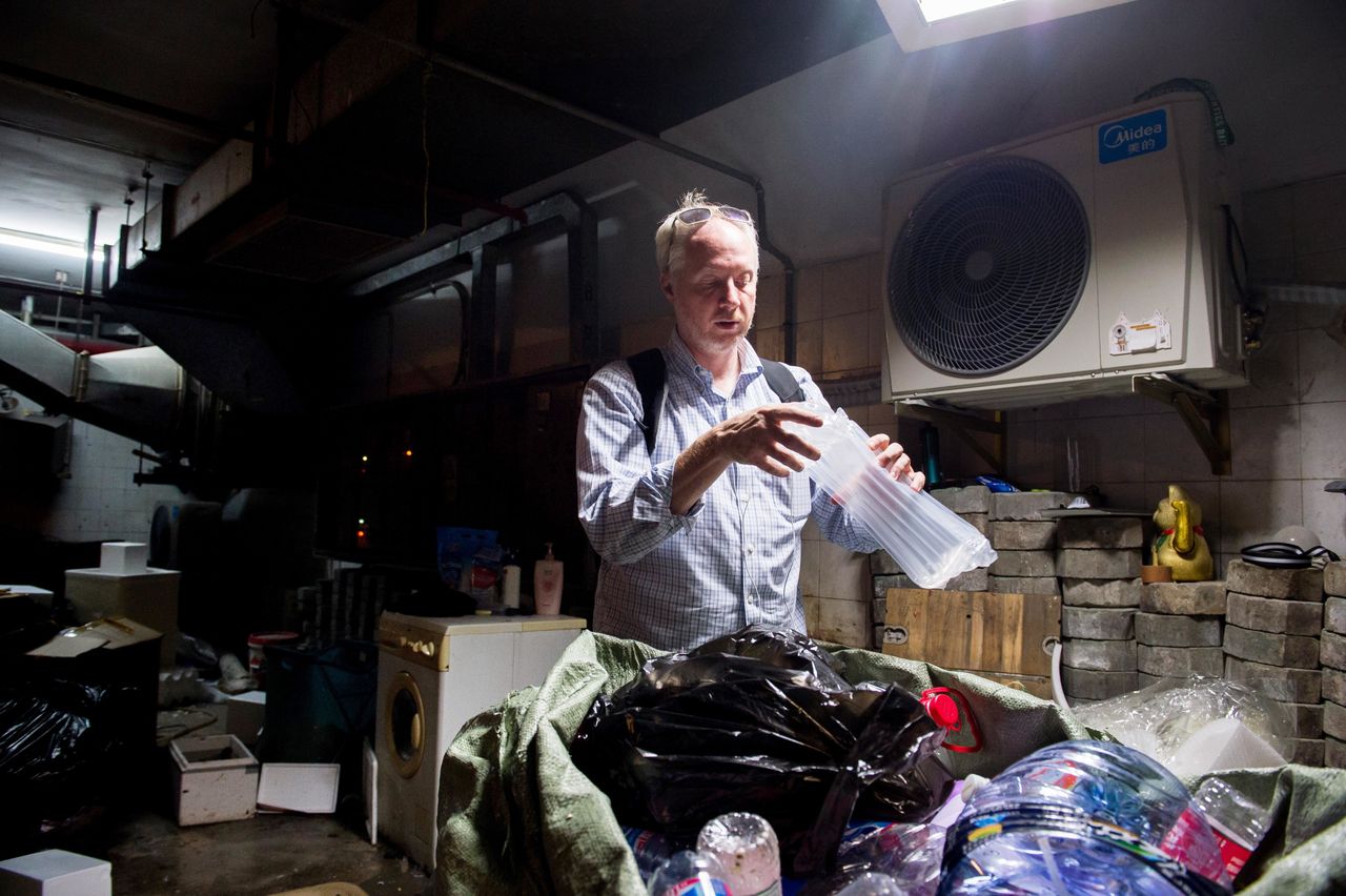 Richard Brubaker, founder of Collective Responsibility, picks up some recyclable waste in the basement of the apartment complex.