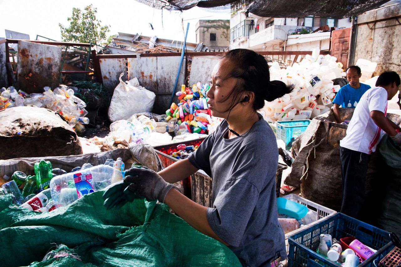 An informal recycler in Shanghai sorting through bags of plastic waste.