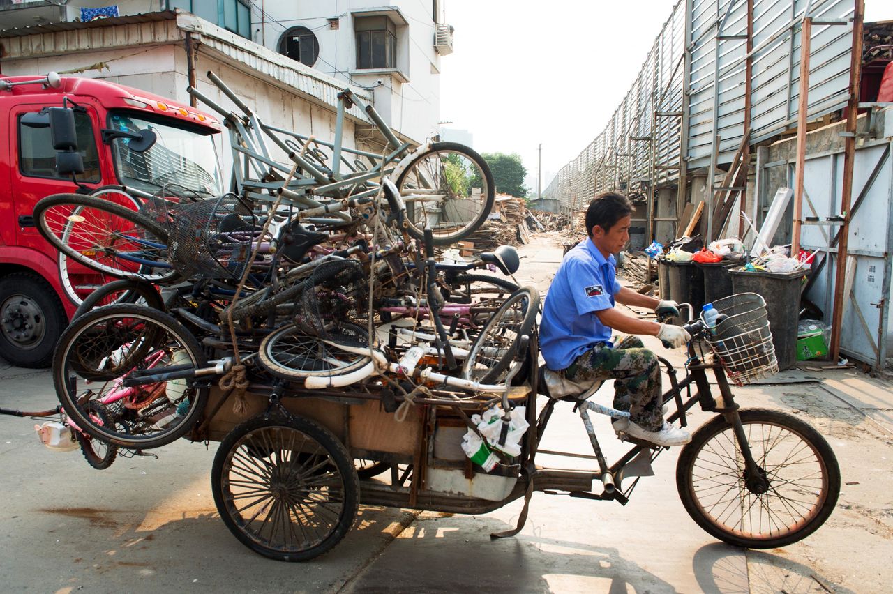 An recycler rides on the streets of Shanghai with a pile of bicycles.