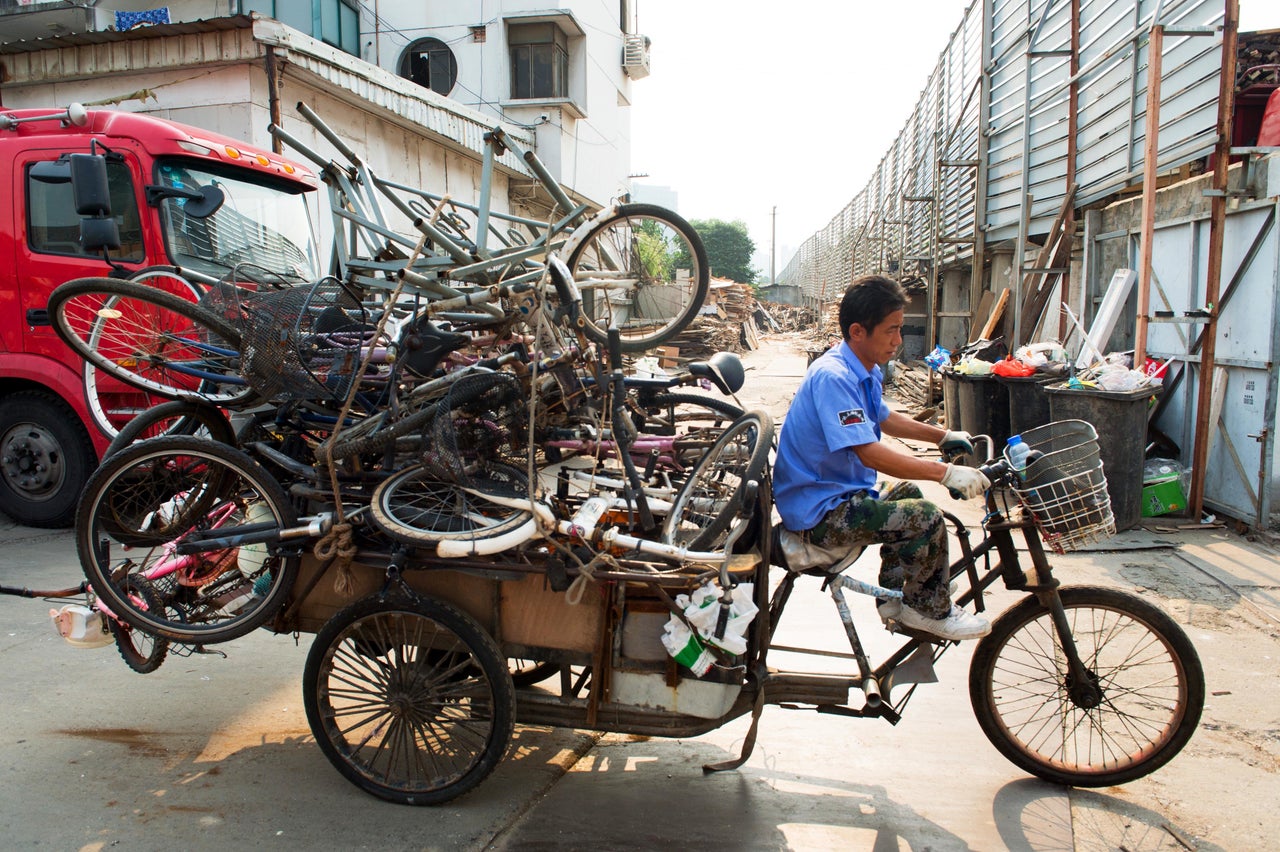 An recycler rides on the streets of Shanghai with a pile of bicycles.