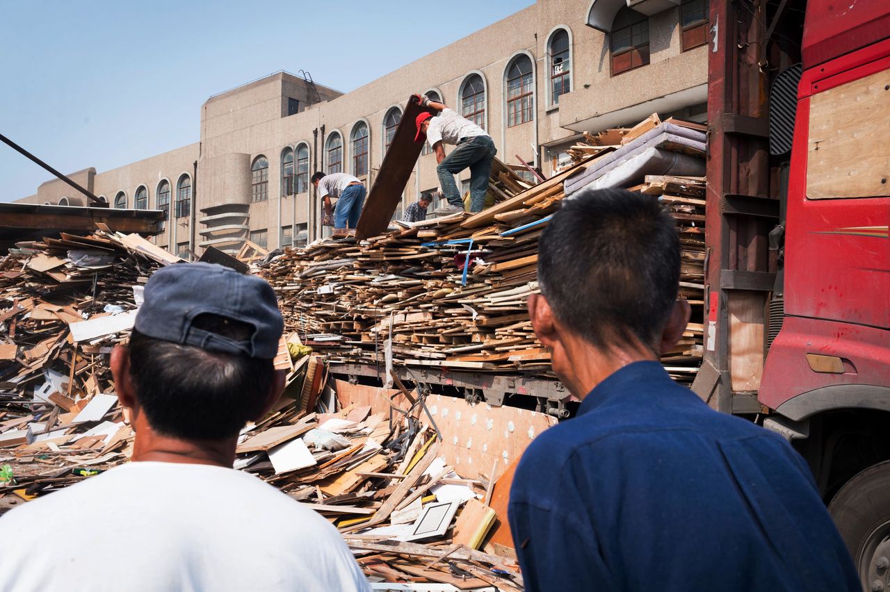 At an informal sorting center in Shanghai, recyclers sift through piles of wood items.