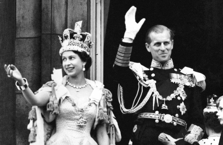 The Queen, wearing the Imperial State Crown, and the Duke of Edinburgh wave from the balcony to the onlooking crowds around the gates of Buckingham Palace after the coronation