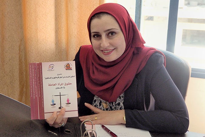 Ayk Sbaihat showing a booklet on Palestinian women’s labour rights, produced by the Reconciliation Units of Kannanyat.