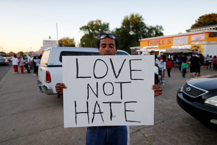 Everett Mathews holds a sign as community members gather for a vigil at the Triple S Food Mart after the U.S. Justice Departm
