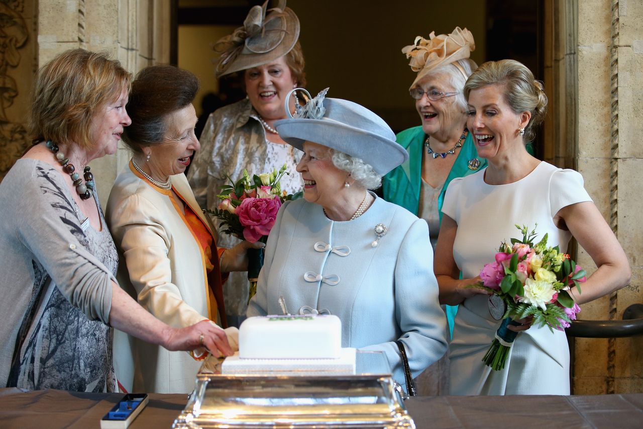 'This is what I call an unscripted moment... You can see she's just having a laugh'. Sophie, Countess of Wessex and Princess Anne look on as the Queen cuts a Women's Institute Celebrating 100 Years cake at its centenary.