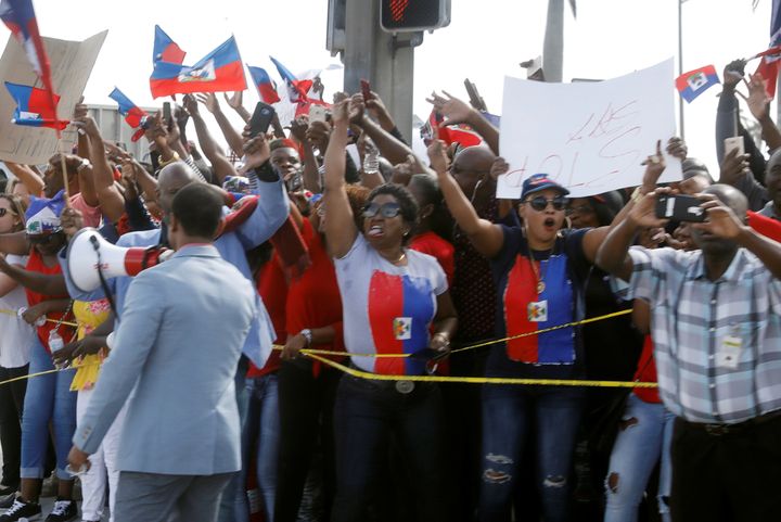 Demonstrators hold up Haitian flags and shout as President Donald Trump's motorcade passes in West Palm Beach, Florida, on Jan. 15, 2018.