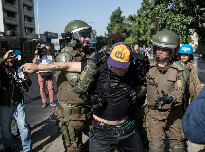 Riot police officers struggle with a protester during a demonstration against the visit of Pope Francis to Chile.