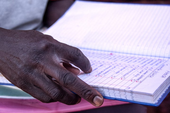 Joe Otoo, a volunteer nurse, keeps records of all the people he cares for in the area.