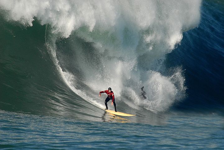 Ryan Seelbach rides on while a nearby surfer wipes out at Maverick’s.
