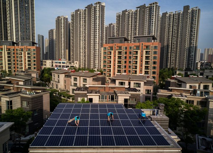 Workers from Wuhan Guangsheng Photovoltaic Company install solar panels on the roof of a building in Wuhan, China. In August, China announced it had already eclipsed its 2020 goal in solar installations.
