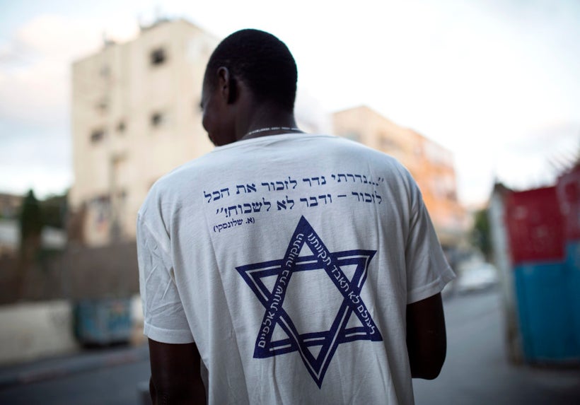 <em>An African migrant wears a T-shirt with a Hebrew phrase referring to the Holocaust," I promise to remember... and ne
