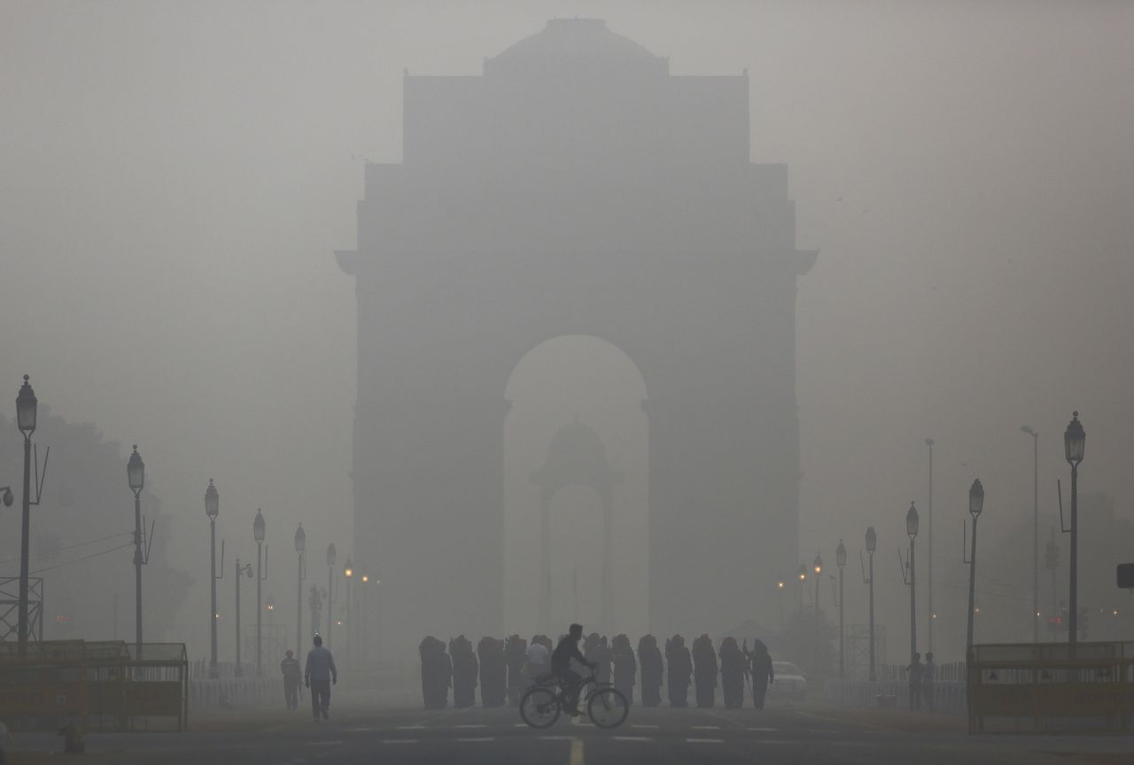 A man rides his bicycle in front of India gate in New Delhi. 